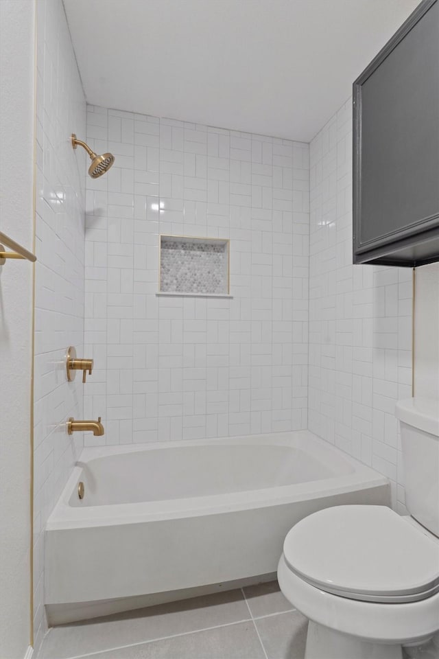 bathroom with toilet, tile patterned flooring, and tiled shower / bath