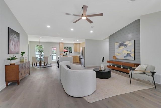 living room featuring ceiling fan, vaulted ceiling, and light hardwood / wood-style floors