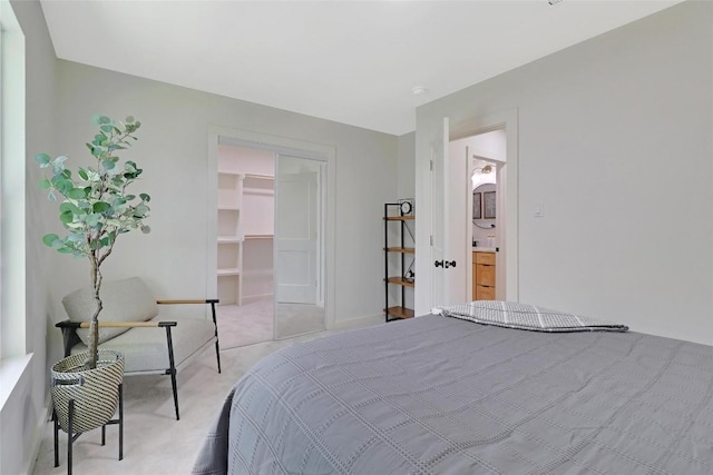 bedroom with light carpet, a closet, a walk in closet, and baseboards