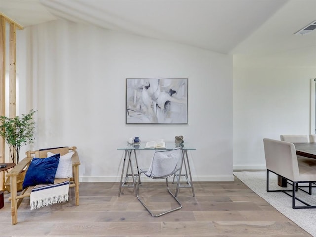 home office with visible vents, vaulted ceiling, baseboards, and wood finished floors