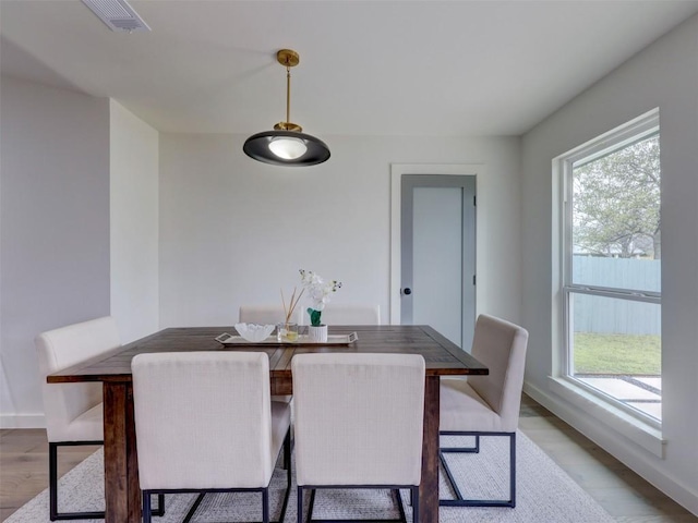 dining room with light wood-type flooring, plenty of natural light, visible vents, and baseboards