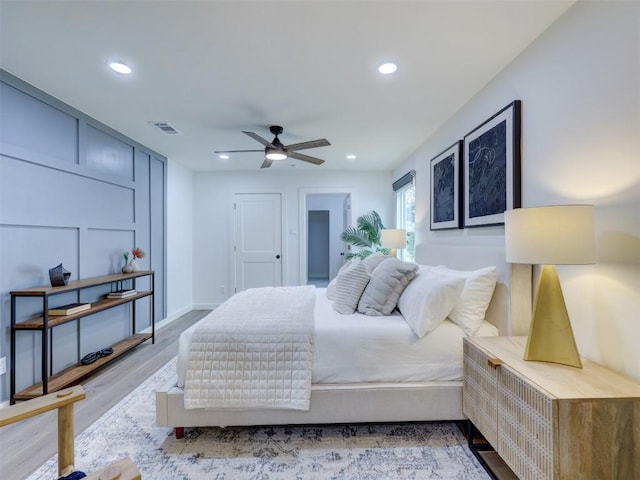 bedroom featuring a decorative wall, recessed lighting, wood finished floors, a ceiling fan, and visible vents