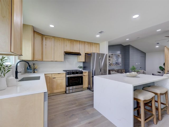 kitchen featuring visible vents, light wood-style flooring, stainless steel appliances, light brown cabinetry, and a sink