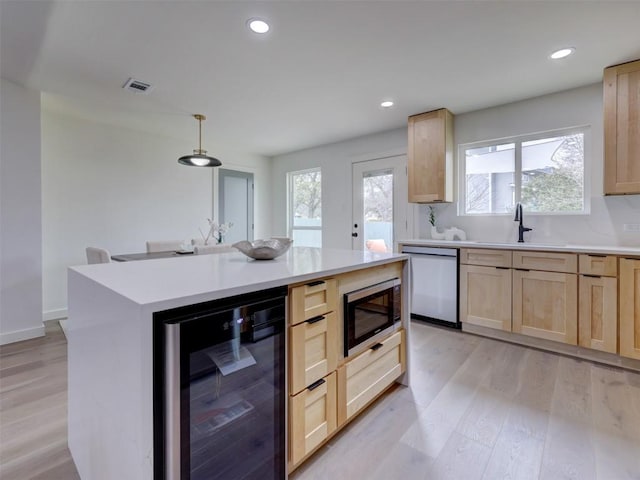 kitchen with light brown cabinets, beverage cooler, visible vents, appliances with stainless steel finishes, and light wood-type flooring