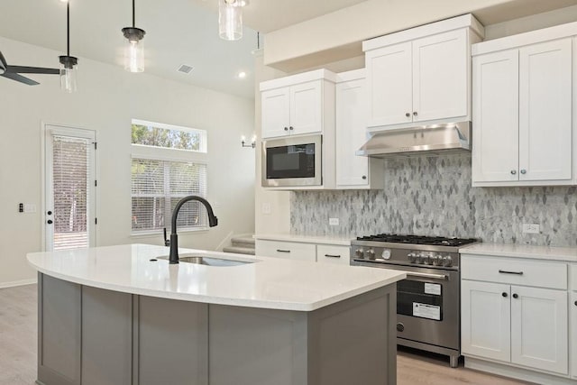 kitchen with built in microwave, sink, high end stove, and white cabinets