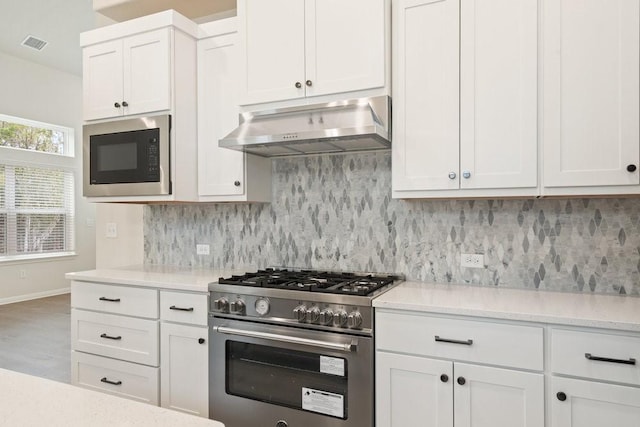 kitchen featuring extractor fan, built in microwave, white cabinets, decorative backsplash, and stainless steel range