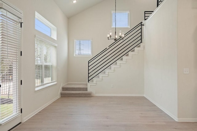 entrance foyer featuring an inviting chandelier, high vaulted ceiling, and light wood-type flooring