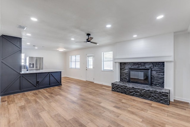 unfurnished living room with ceiling fan, light wood-type flooring, and a fireplace