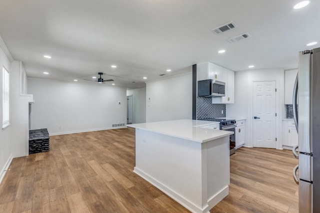 kitchen featuring stainless steel appliances, ceiling fan, light hardwood / wood-style flooring, white cabinetry, and backsplash