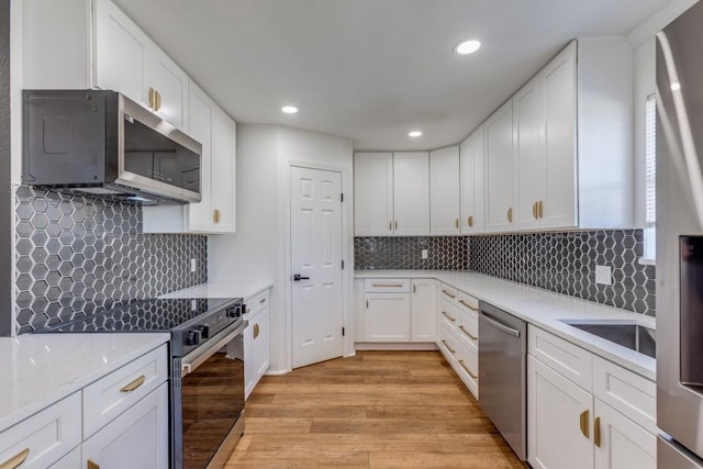 kitchen with stainless steel appliances, light hardwood / wood-style floors, white cabinets, and tasteful backsplash