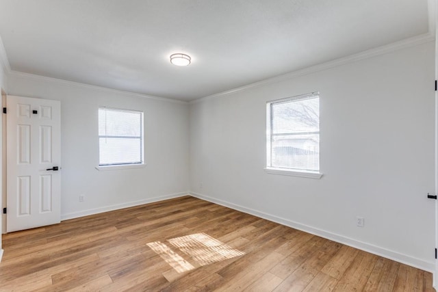 empty room with ornamental molding, a healthy amount of sunlight, and light wood-type flooring