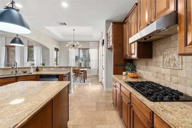 kitchen with black gas cooktop, a sink, under cabinet range hood, brown cabinetry, and tasteful backsplash
