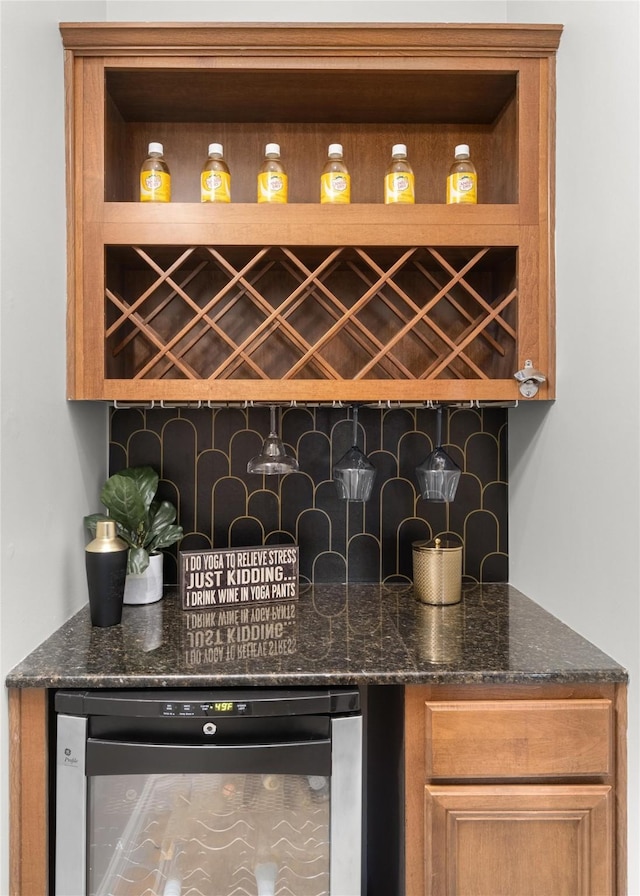 bar featuring dark stone counters, beverage cooler, and dishwashing machine