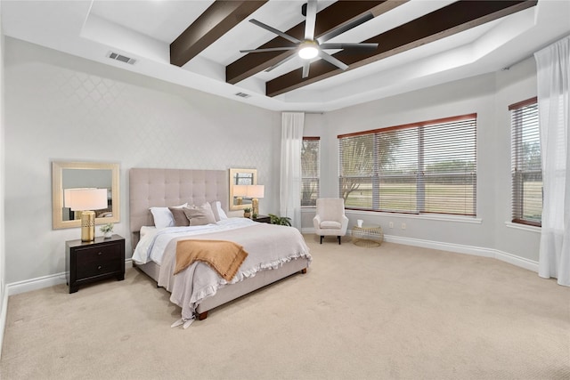 carpeted bedroom with ceiling fan and a tray ceiling