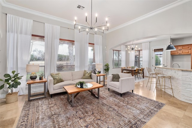 living room featuring a healthy amount of sunlight, ornamental molding, and a chandelier