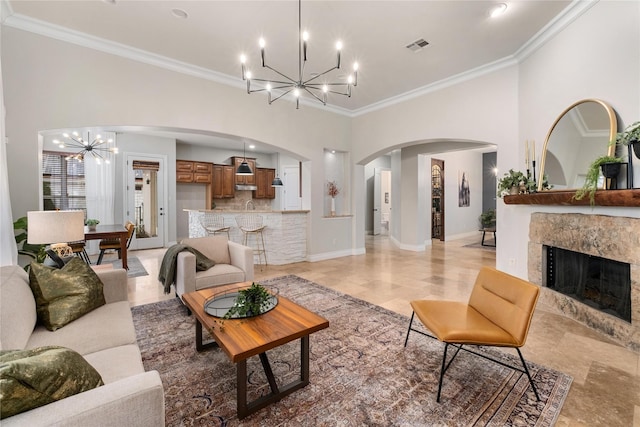 living room with ornamental molding, a fireplace, and a notable chandelier