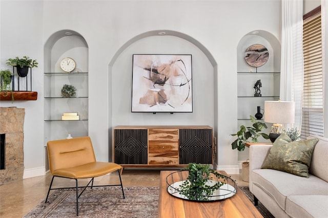 living area featuring a tiled fireplace, built in features, and a wealth of natural light