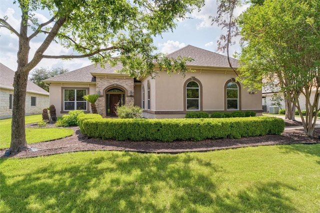 view of front facade featuring stucco siding, a front lawn, a shingled roof, and central AC unit