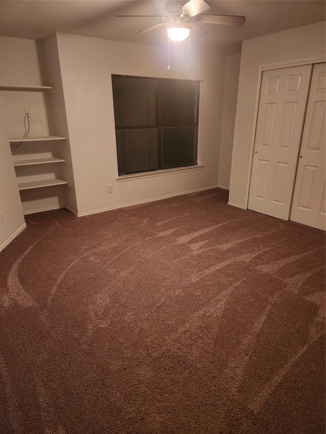 unfurnished bedroom with ceiling fan and dark carpet