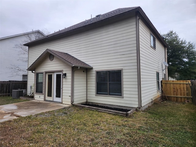 back of property with central AC unit, a lawn, and a patio