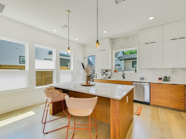 kitchen featuring white cabinetry, hanging light fixtures, a center island, and dishwasher