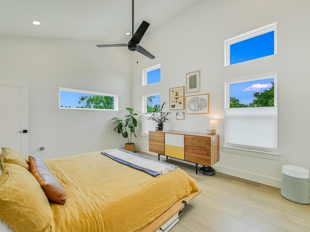 bedroom featuring a towering ceiling, ceiling fan, and light wood-type flooring