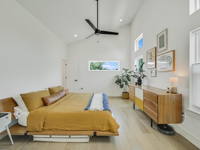 bedroom with ceiling fan, high vaulted ceiling, and light wood-type flooring