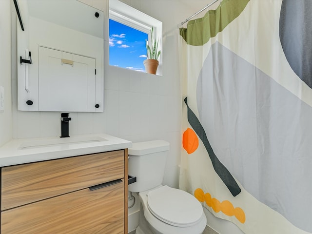 bathroom with tile walls, vanity, curtained shower, and toilet