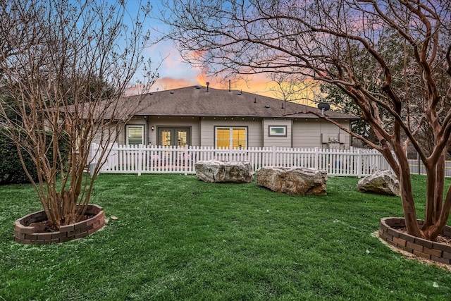 back house at dusk with a lawn