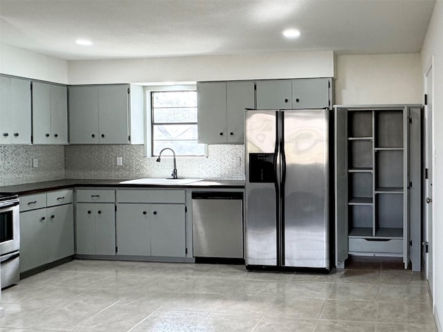 kitchen with decorative backsplash, appliances with stainless steel finishes, sink, and gray cabinetry