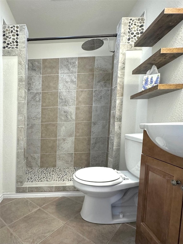 bathroom featuring toilet, vanity, tile patterned floors, and tiled shower