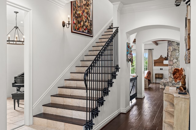 stairs with crown molding, a fireplace, hardwood / wood-style floors, and a notable chandelier