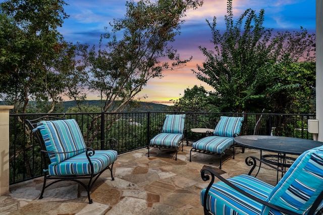 patio terrace at dusk featuring a mountain view and a balcony