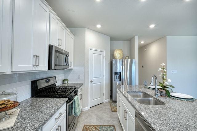 kitchen with light stone countertops, appliances with stainless steel finishes, white cabinetry, and sink