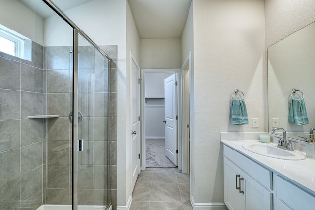 bathroom with tile patterned flooring, walk in shower, and vanity