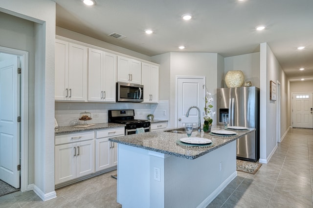 kitchen featuring a center island with sink, stainless steel appliances, decorative backsplash, white cabinets, and sink