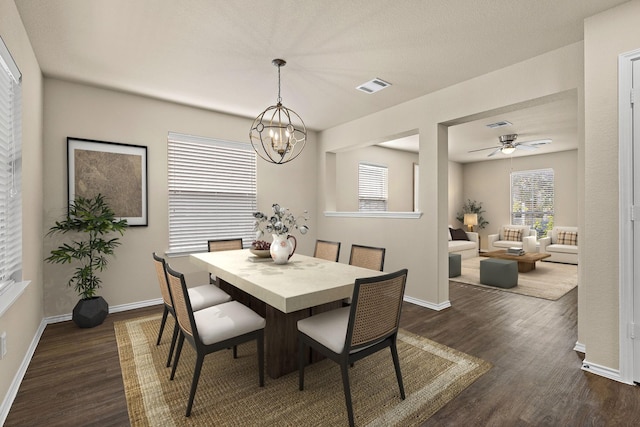 dining area with dark wood-type flooring and ceiling fan with notable chandelier