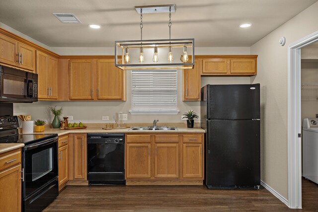 kitchen with pendant lighting, black appliances, washer / dryer, sink, and dark hardwood / wood-style floors