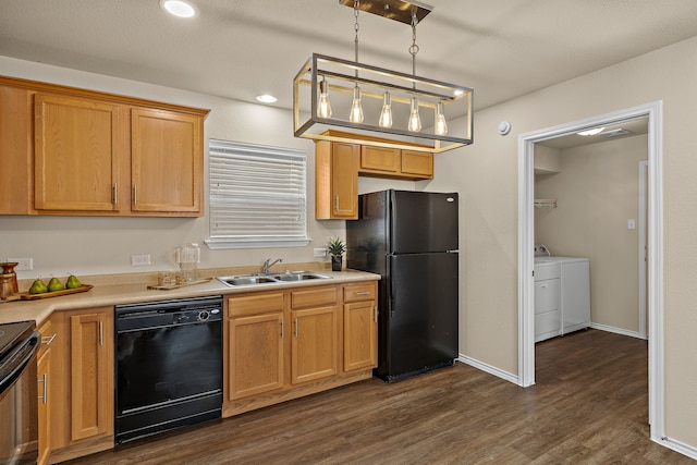 kitchen with washer and dryer, pendant lighting, black appliances, sink, and dark wood-type flooring