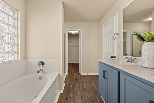 bathroom featuring vanity, a bath, a healthy amount of sunlight, and hardwood / wood-style floors