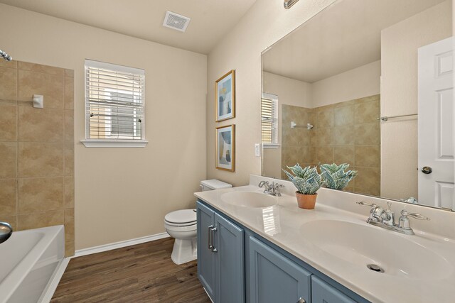 full bathroom featuring toilet, tiled shower / bath, wood-type flooring, and vanity