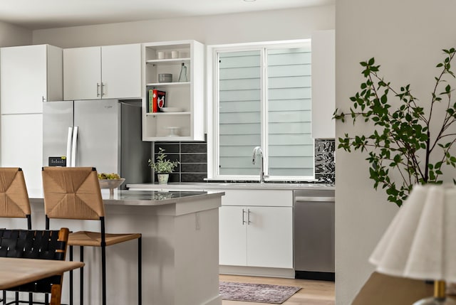 kitchen with stainless steel counters, white cabinets, dishwasher, and a breakfast bar area