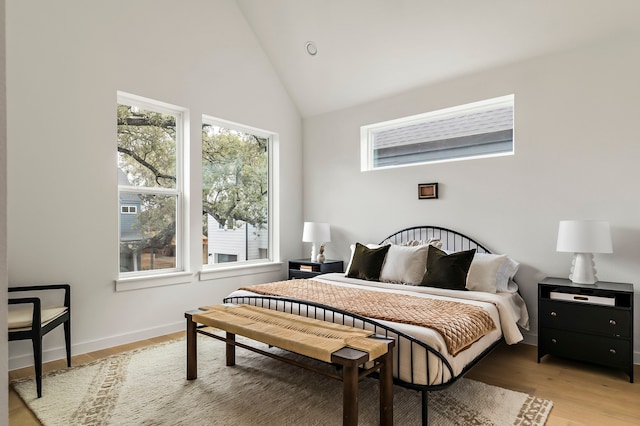 bedroom with light hardwood / wood-style floors and high vaulted ceiling