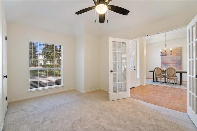 tiled empty room with ceiling fan with notable chandelier, carpet floors, french doors, and baseboards