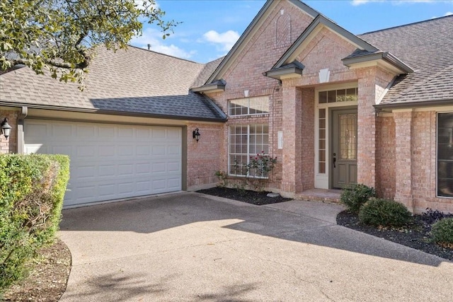 view of front of home featuring a shingled roof, an attached garage, and brick siding