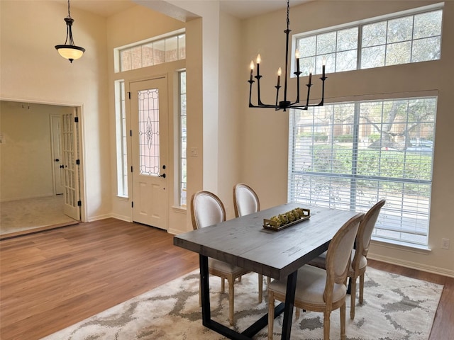 dining area with baseboards, a high ceiling, and wood finished floors