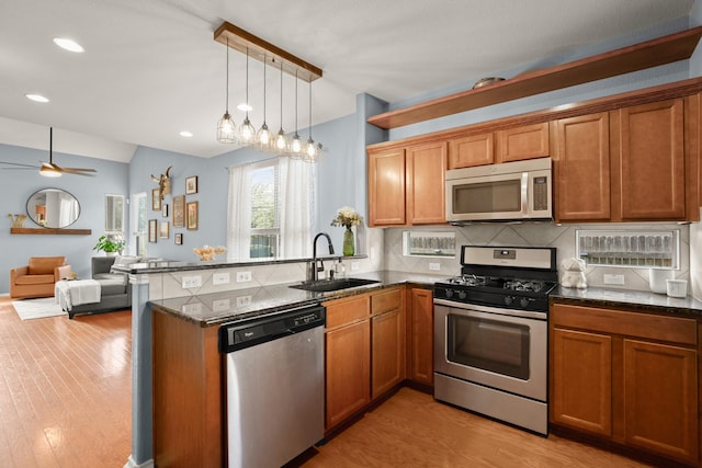 kitchen featuring pendant lighting, sink, stainless steel appliances, and kitchen peninsula