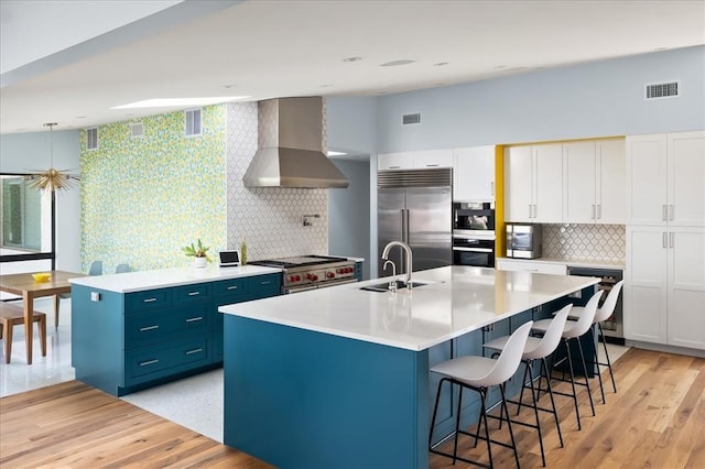 kitchen featuring white cabinets, sink, island range hood, a kitchen island with sink, and high quality appliances