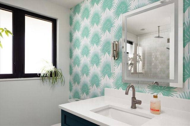 bathroom with tiled shower and vanity