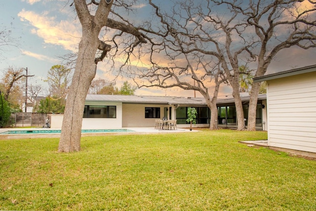 back of house at dusk featuring a patio, fence, a fenced in pool, a lawn, and metal roof